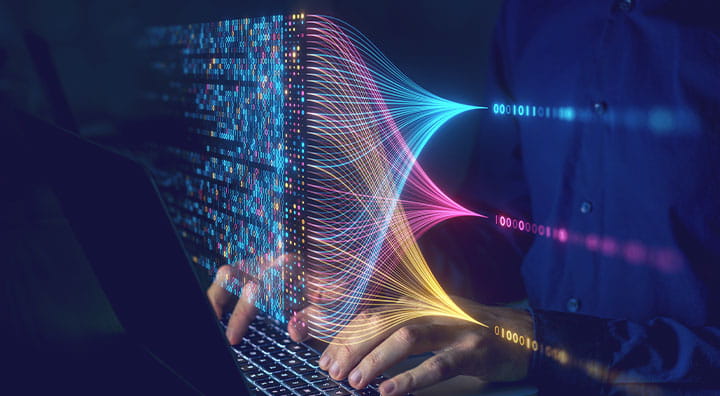 A person typing on a laptop, with colorful digital patterns emanating from the screen, symbolizing data flow.