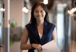 Person standing in an office holding a file.