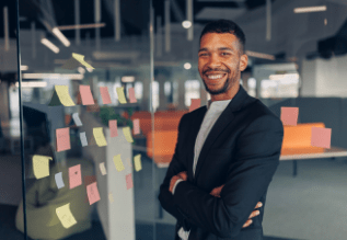 A person standing in front of a glass wall with sticky notes.