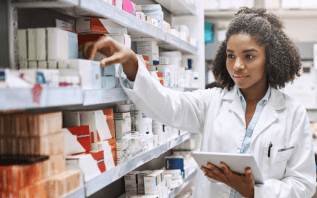 A pharmacist working and holding a tablet device.