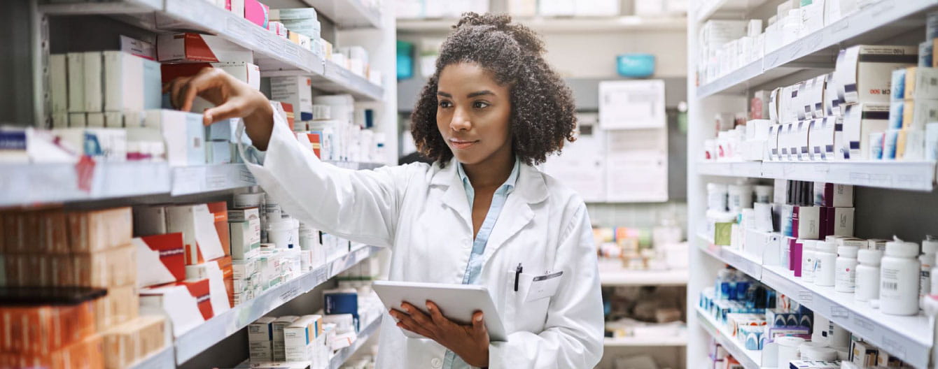 A pharmacist working and holding a tablet device.