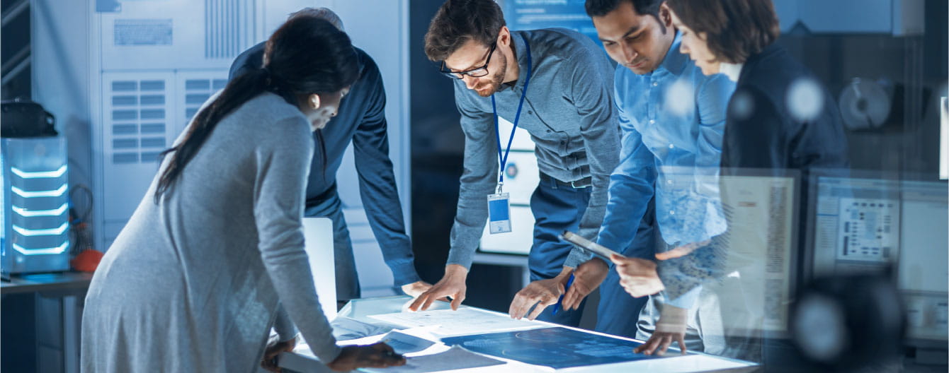 A group of people standing around a desk filled with papers.