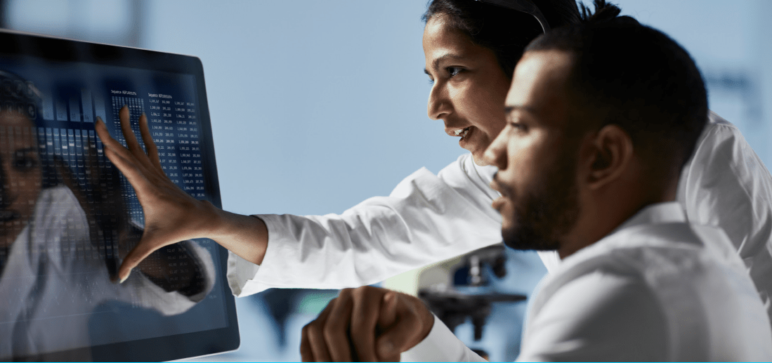 a man and woman in white coat looking at a computer screen