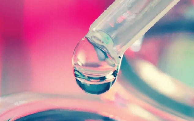 Liquid drop coming out of a pipette.