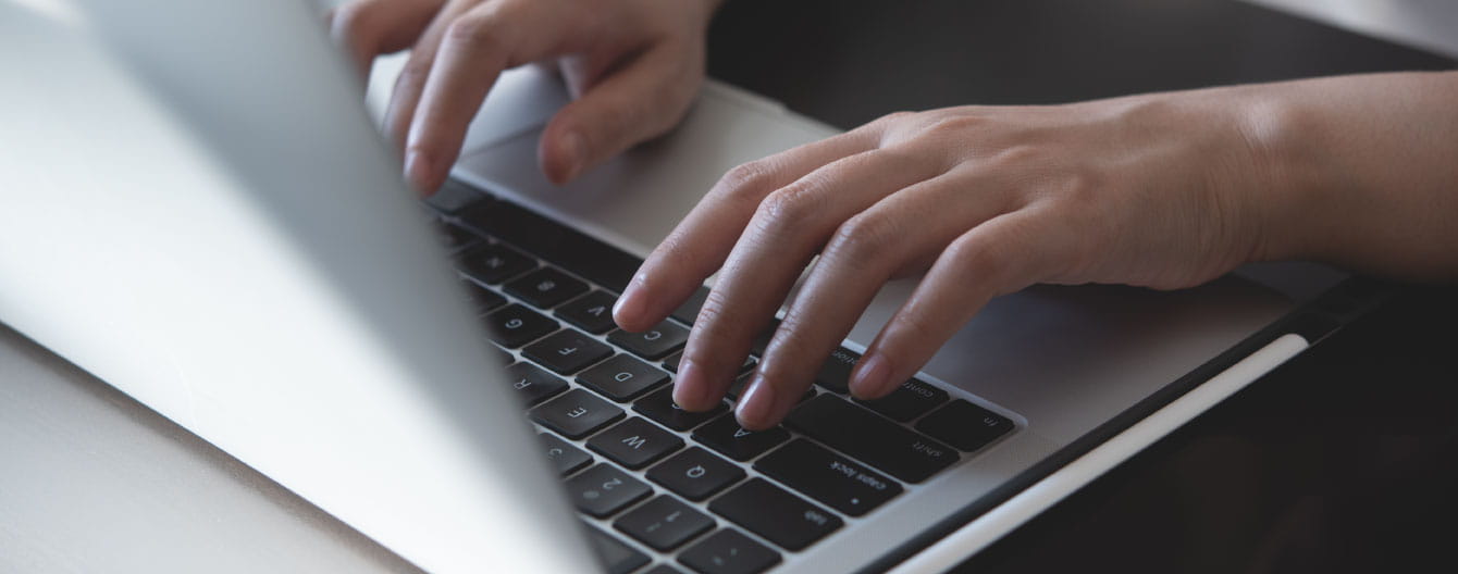 Hands typing on a laptop device.