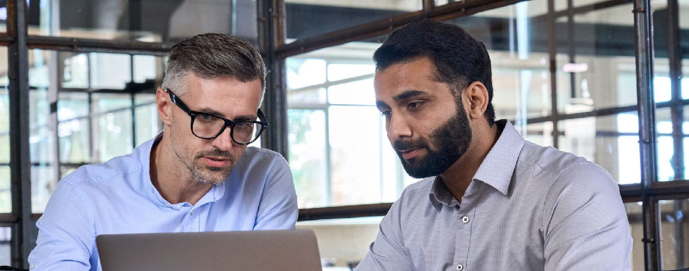 Two people discussing in front of a laptop device.