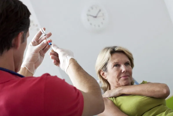 Healthcare worker preparing for an injection in front of a patient.