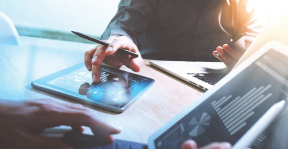 Professionals analyzing data trends on digital devices.