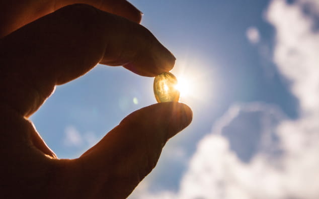 Hand holding a pill into the sky.