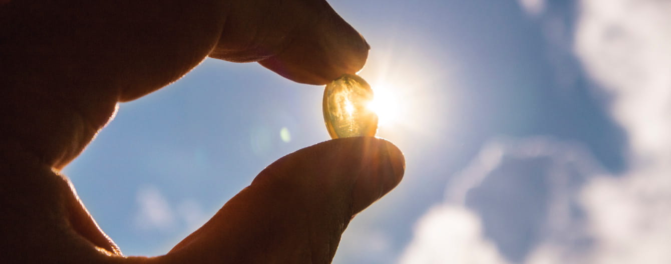 Hand holding a pill into the sky.