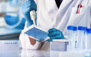 a person in a lab coat holding a plastic container with blue circles
