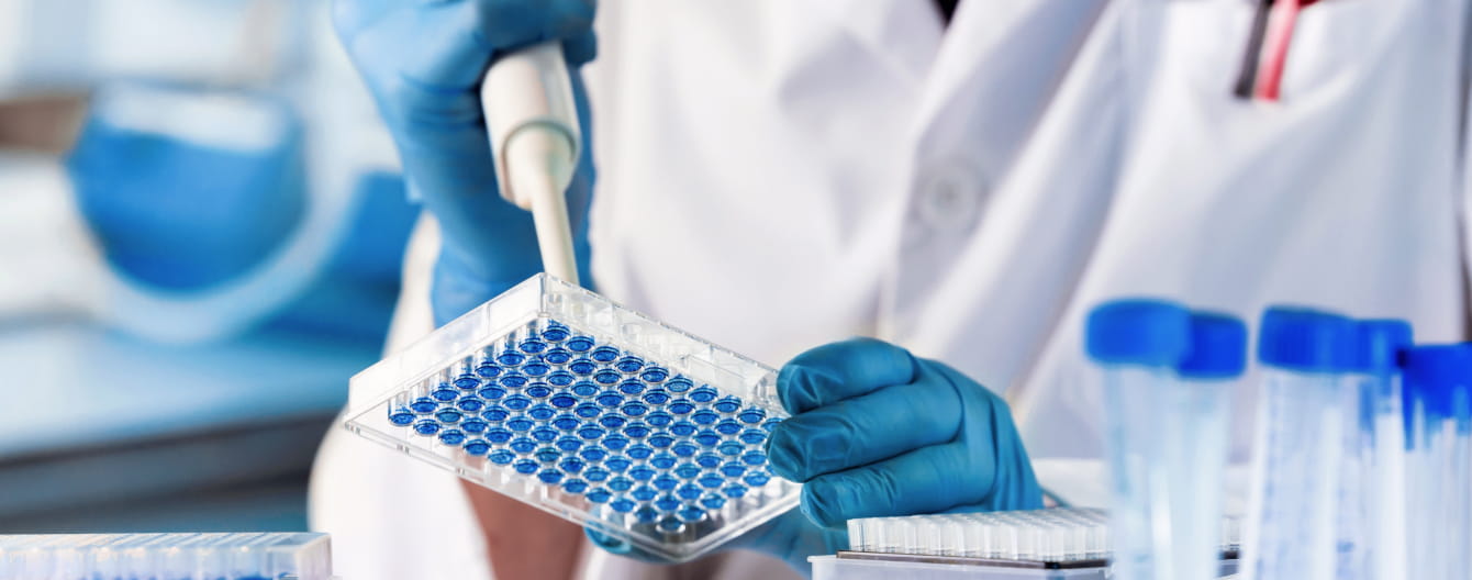 a person in a lab coat holding a plastic container with blue circles