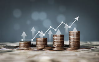 Stacks of coins arranged in ascending order with a white arrow and line graph overlay indicating growth