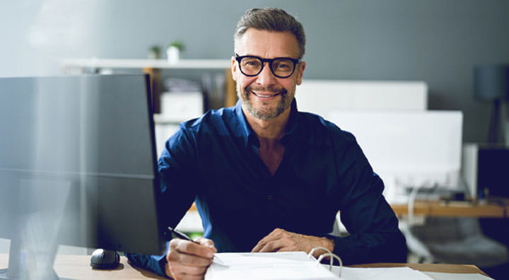 A person in a blue shirt sits at a desk working on a client's clinical trial disclosure.