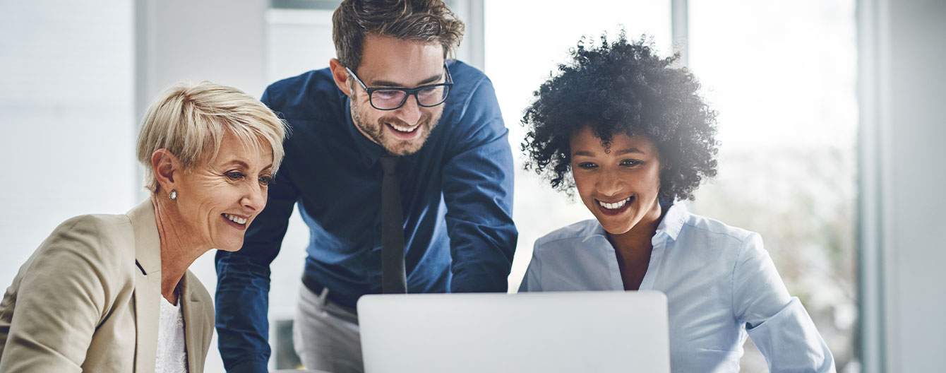 A group of professionals collaborate around a laptop.