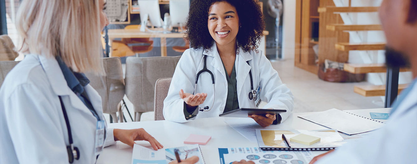 A diverse group of doctors discussing medical reports and analyzing data during a meeting.