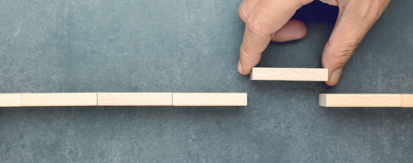 A conceptual image of a hand placing a wooden block to bridge a gap.