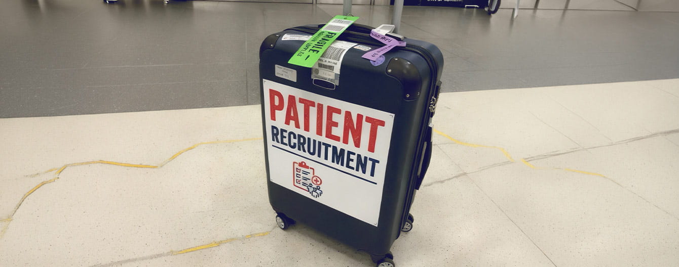 A dark hardside spinner suitcase with a large white sign reading "PATIENT RECRUITMENT"