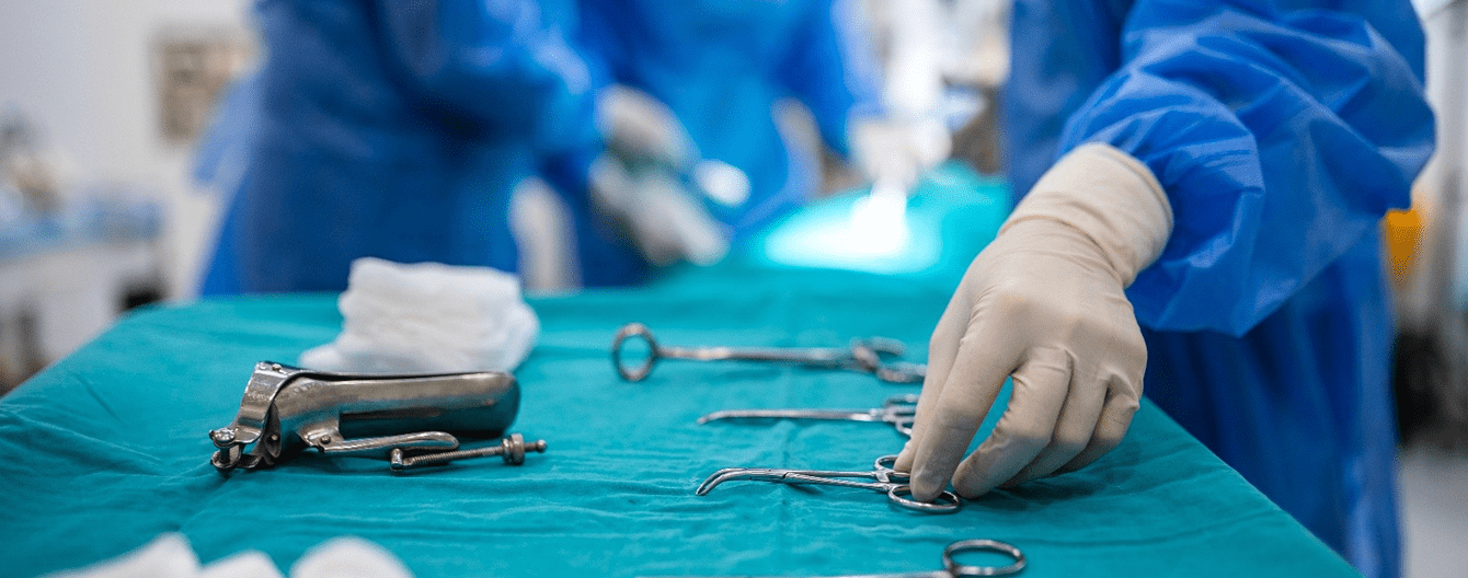 Gloved hand selecting surgical tools on a sterile drape