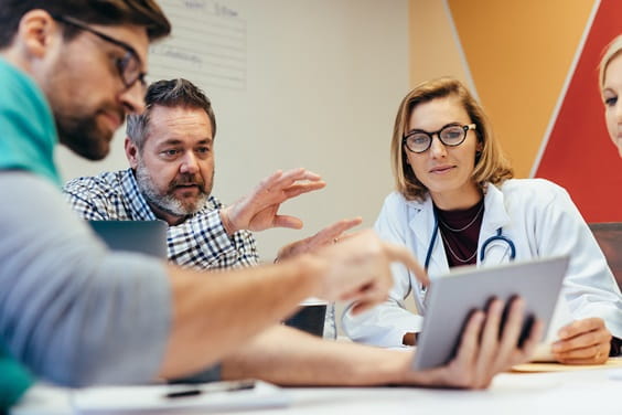 Group of people discussing around a tablet device.